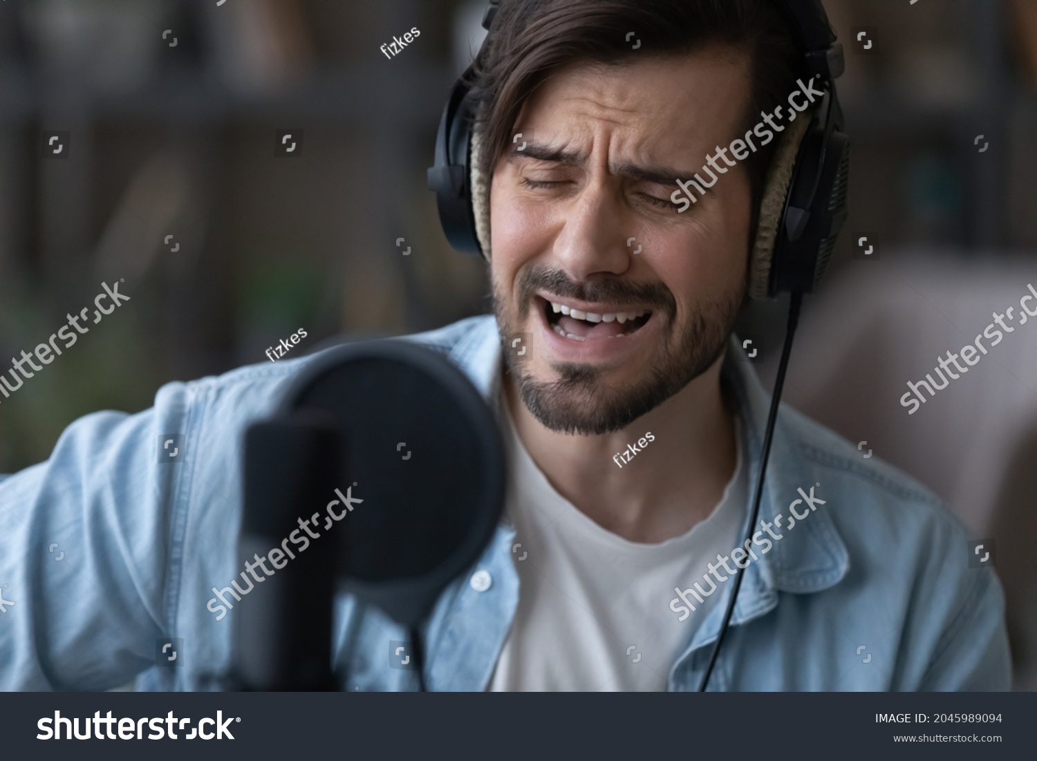 stock-photo-close-up-man-in-headphones-singing-using-professional-microphone-with-pop-filter-musician-singer-2045989094