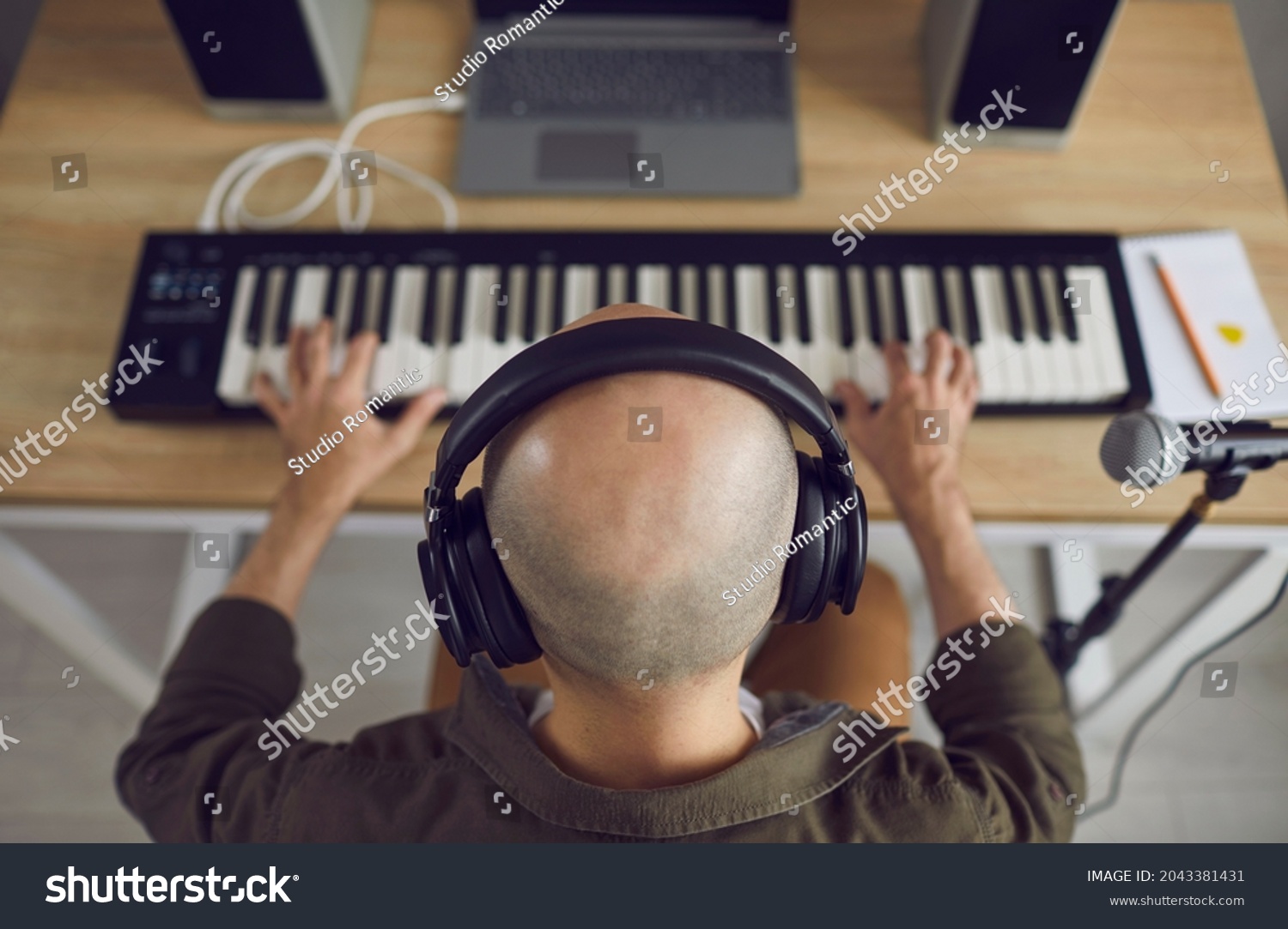 stock-photo-high-angle-closeup-shot-from-above-of-creative-talented-bald-headed-pianist-wearing-headphones-2043381431